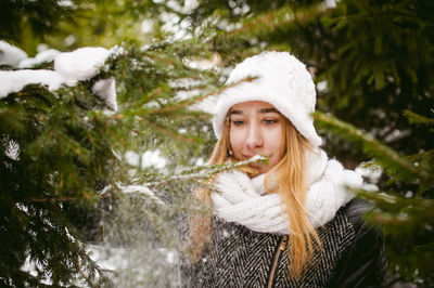 Young woman wearing warm clothing while standing by trees during winter