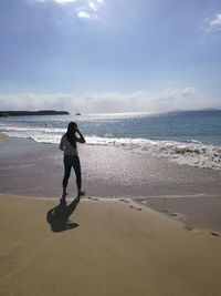 Girl walking on shore at beach against sky