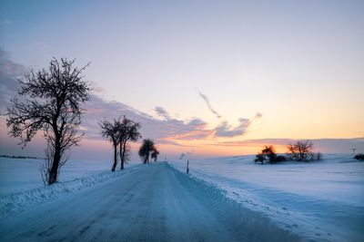 Scenic view of snow covered road against sky during sunset