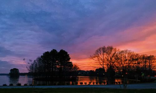 Silhouette trees by lake against sky during sunset