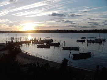 Boats moored in sea against sky during sunset