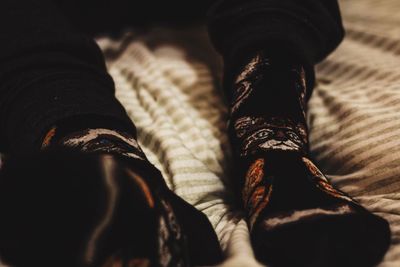 Low section of woman wearing socks while sitting on bed at home