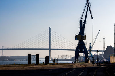 Suspension bridge over river against clear sky