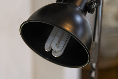 Close-up of electric lamp hanging against wall