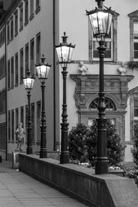 Row of illuminated gas lights on retaining wall against building in city