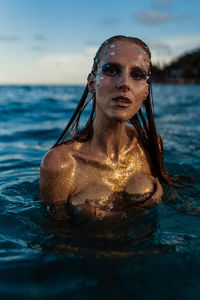 Young woman with golden skin in water