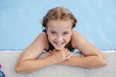 High angle portrait of smiling girl leaning at poolside