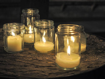 Lit candles in mason jars on table