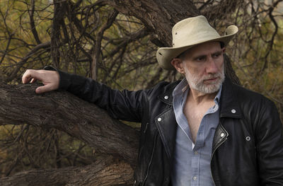 Portrait of adult man in cowboy hat against tree