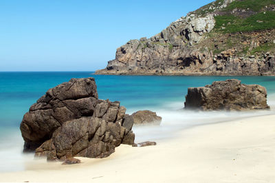 Rocks on beach against clear blue sky