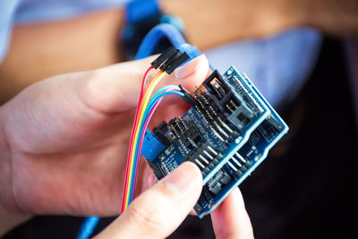 Cropped hands repairing circuit board in workshop