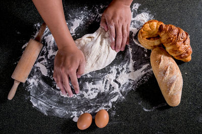 Directly above shot of hands kneading dough on table