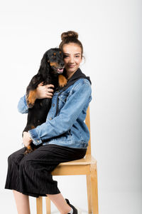 Portrait of smiling young woman holding dog against white background