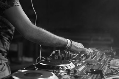 Midsection of dj adjusting sound mixer in nightclub