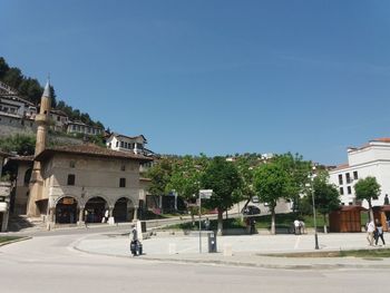 Street by buildings against clear blue sky