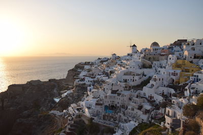 Buildings by sea against sky during sunset