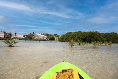 Sun shines through the clouds over a green kayak in the water of new pass in bonita springs, florida