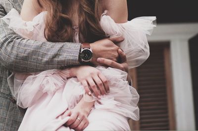 Midsection of couple embracing at home