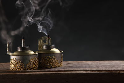 Close-up of oil lamps on wooden table against black background