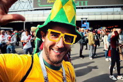 Portrait of smiling young man wearing cap and eyeglasses outside stadium