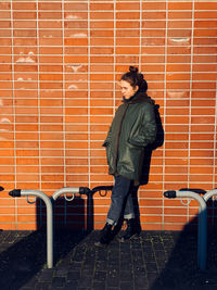 Side view of girl standing against brick wall