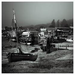 Boats moored at harbor against clear sky