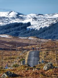 Scenic view of snowcapped mountains against sky with lone cyclist on single-track road 