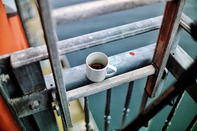 High angle view of cigarette butts in coffee cup on ladder