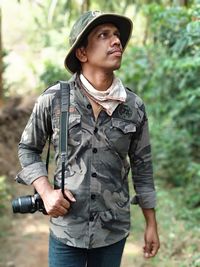 Man with camera looking up in forest