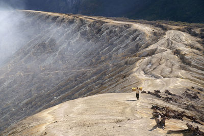 High angle view of man carrying sulphur at ijen crater