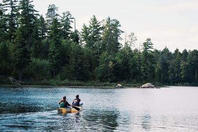 Rear view of two people canoeing in water