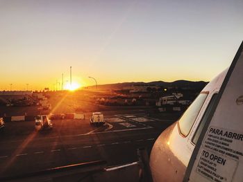 Airplane on runway against sky during sunset