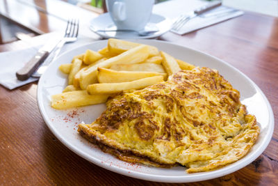 Close-up of omelet with french fries served in plate on table