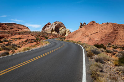 Road leading towards mountains against sky