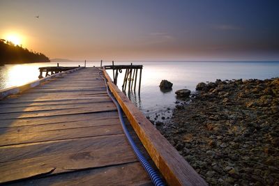 Pier over sea against sky during sunset