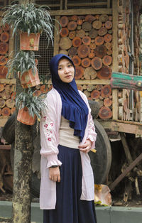 Portrait of smiling young woman standing by plants