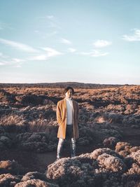 Man standing on rock against sky