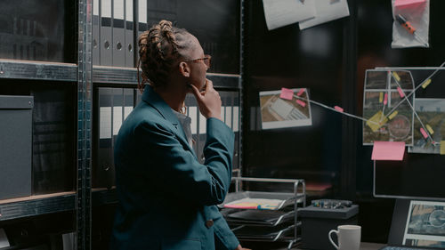 Side view of young woman looking through window