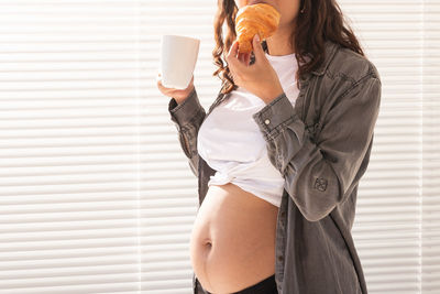 Midsection of woman standing against wall