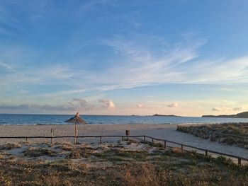Rear view of woman standing on beach against sky during sunset