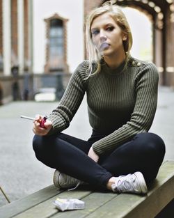 Young woman using phone while sitting on camera