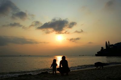 Silhouette people on beach against sky during sunset