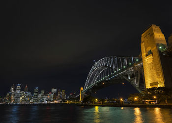 Illuminated city by river at night