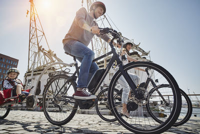 Germany, hamburg, family riding e-bikes at the harbor