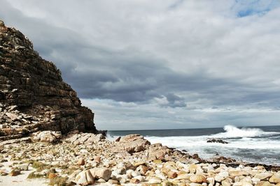 Rock formation by sea against sky