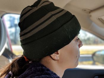 Close-up of young woman wearing knit hat in car