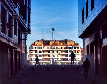 People walking on road amidst buildings in city