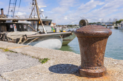 Close-up of retaining wall moored at harbor against sky