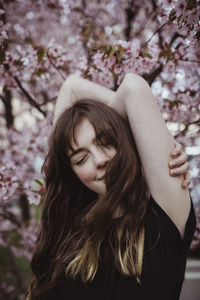 Smiling woman with eyes closed against tree