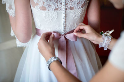 Midsection of bride holding wedding dress